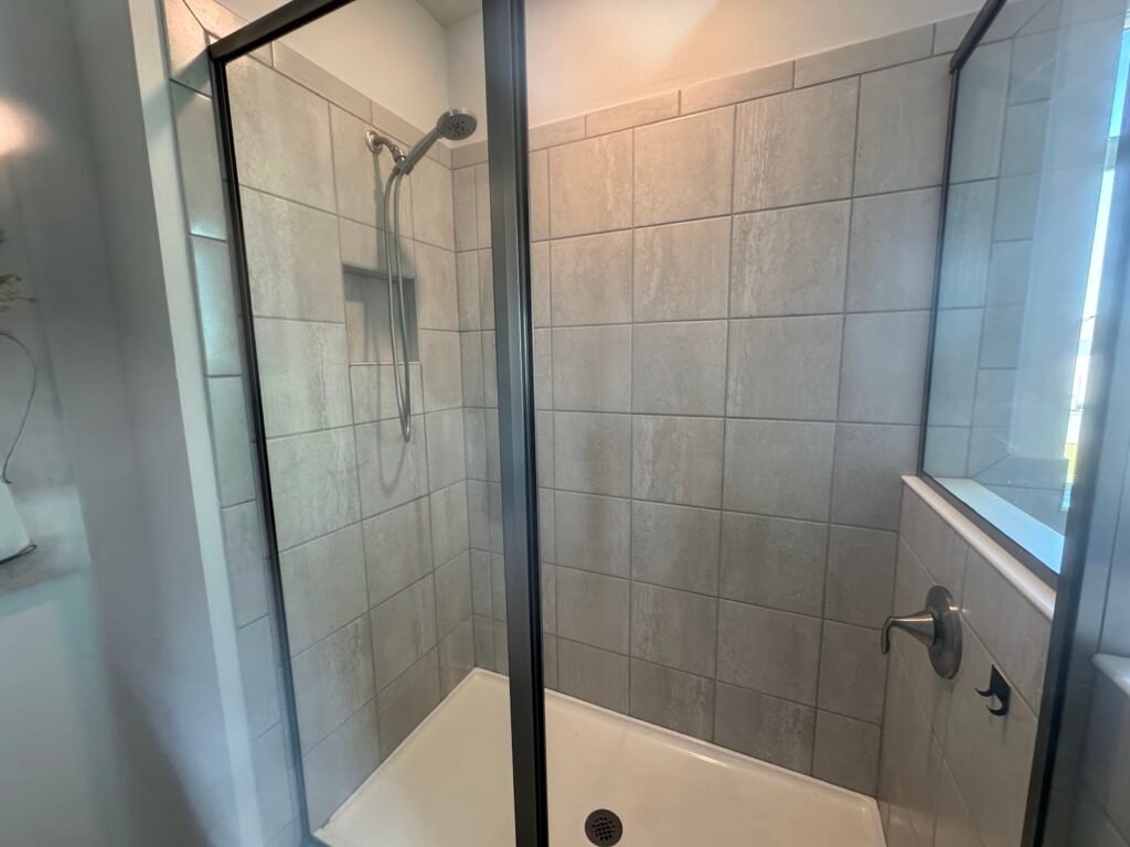 Restored tile shower with clean grout and glass door